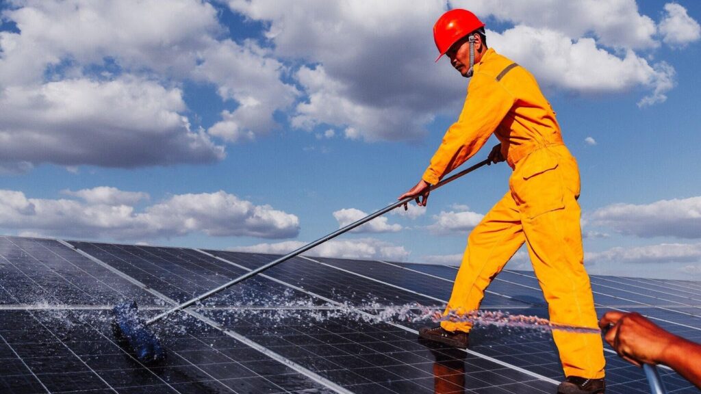 a man wearing an orange work suit offering professional solar panel cleaning services